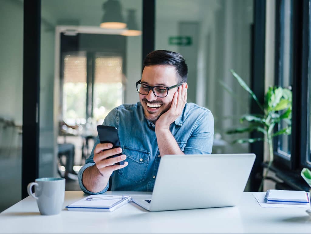Smiling businessman using phone in home or office. Small busines