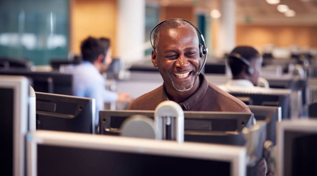 Businessman Wearing Headset Talking To Caller In Customer Services Department