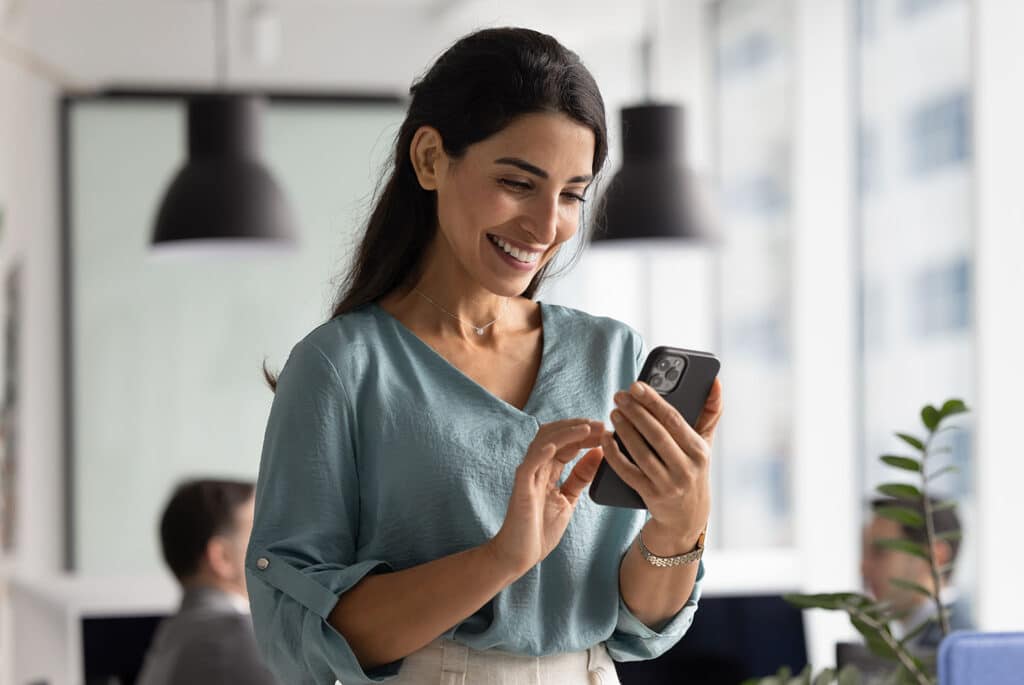 Businesswoman using web service on smartphone in office workspace